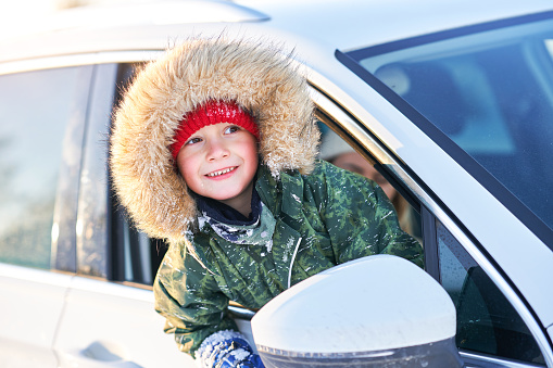 Young happy boy in the car during winter. High quality photo