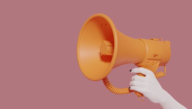 istock A woman's hand holding a orange megaphone isolated on a pink background. Creative announcement concept. Loud voice of women. Women's rights and voice. Advertisement mock up with copy space for text. 1359488473