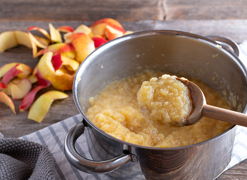 Traditional fresh cooked applesauce. Served in a saucepan and wooden spoon on rustic table.