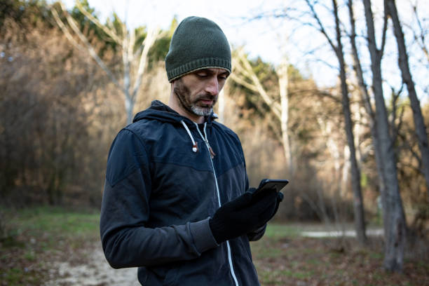istock Handsome young athlete man using a mobile phone at the forest 1359491026