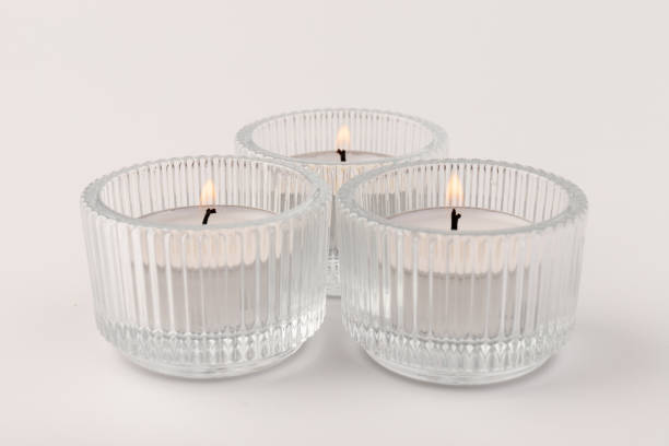 istock Burning tea candles in a glass holder, isolated on white. Space for text 1359491058