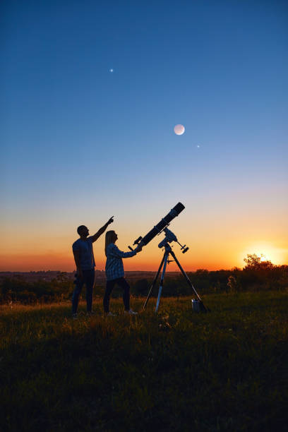 istock Couple stargazing together with a astronomical telescope. 1359492701