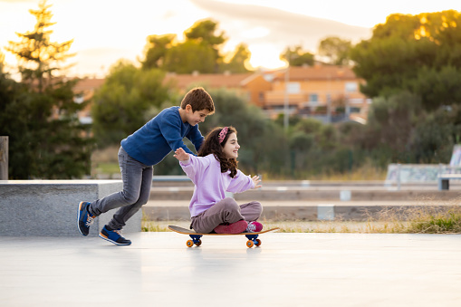 Two friends playing with a skate board