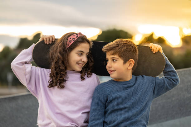 istock Two kids with a skate board at sunset 1359493858
