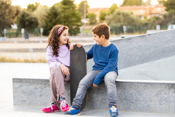 istock Two kids with a skate board at sunset 1359493865