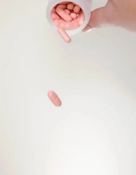 pink pills falling on white background