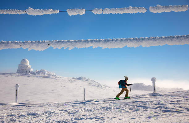 Touring skier walking up in the mountain in cold winter weather, nearby radar dome. This is a popular tourist route at Vitosha mountain, Bulgaria, nearby meteorology station in Bulgaria.