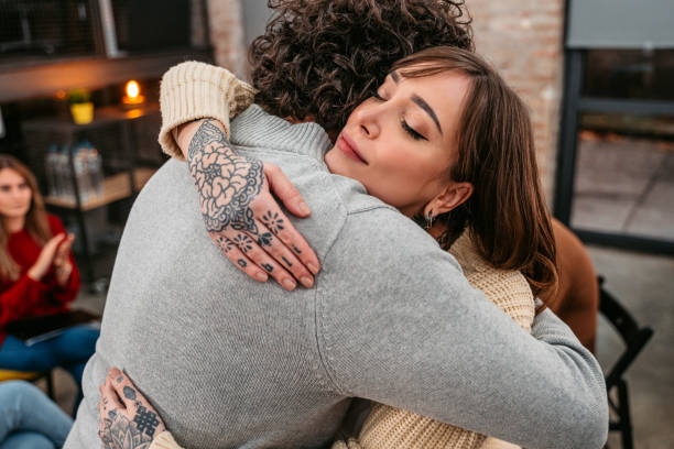 Support group patients hug each other during the therapy session Support group gathering for a meeting. Two people are embracing each other and other members are supporting them. drug abuse stock pictures, royalty-free photos & images
