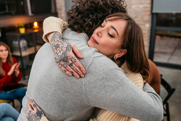 Support group patients hug each other during the therapy session Support group gathering for a meeting. Two people are embracing each other and other members are supporting them. prop stock pictures, royalty-free photos & images