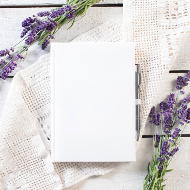Libro bianco bianco con cornice di fiori di lavanda su pizzo bianco e tavola di legno rustico - foto stock