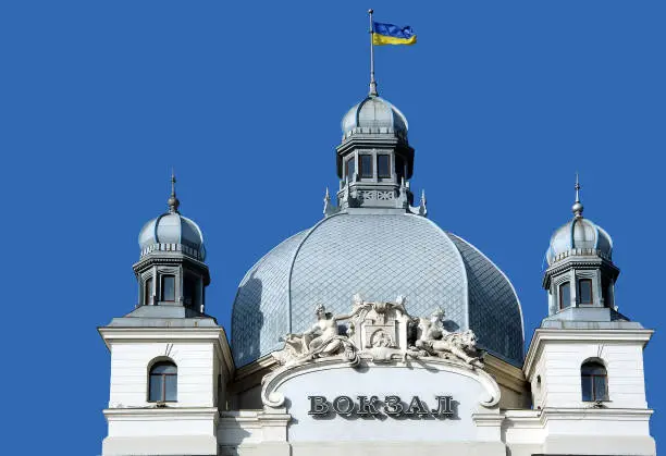 Top of Lviv railway station building with sculptures in Ukraine. The headline means Railway station in English
