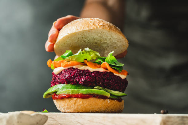 istock Woman putting bread bun on a vegan burger 1359499491