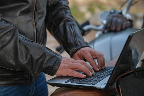 istock Close up of unrecognizable man using a laptop while traveling with his motorcycle. 1359501418