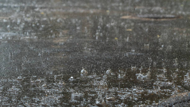 istock Raindrops hitting puddles on a rainy day. Rain drops falling in a big puddle on urban asphalt in the town. 1359502698