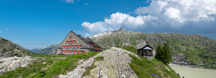 Guttannen, Switzerland - July 23, 2021: Landscape with the historic alpine hotel Grimsel Hospiz and the chapel Hospiz near Guttannen in Valais in Switzerland