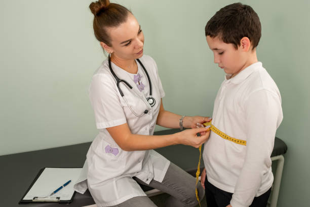 расстраивается мальчик во время измерения талии на приеме у диетолога. - teen obesity стоковые фото и изображения