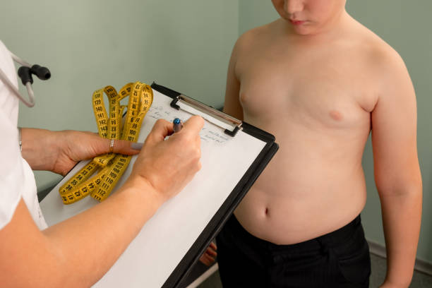 freundlicher ernährungsberater misst die taille. fettleibigkeit bei kindern, gewichtsverlust. - child obesity stock-fotos und bilder