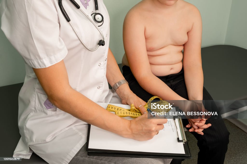 Childhood obesity problem. Fat boy at a nutritionist appointment. Childhood obesity problem and weight loss. Fat boy at a nutritionist appointment. Overweight boy consulting with doctor in office. Doctor examining fat boy in clinic. Doctor measuring overweight boy. Obesity Stock Photo