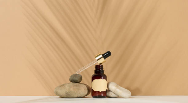 istock a brown glass bottle with a pipette and a brown label stands on a stone. Container for cosmetics, serum and oil. Palm leaf shadow 1359504034