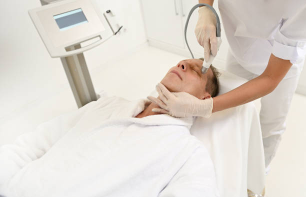 istock Aesthetician performs facelift procedure for mature man using modern ultrasonic equipment in SPA for exfoliation, stimulation and hydration. Men's aesthetic cosmetology and anti-aging skincare concept 1359506408