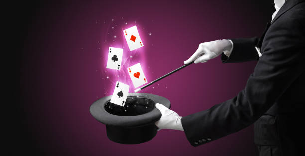 istock Magician making trick with wand and playing cards 1359507527