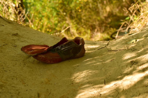 On the sand in the pit lies a forgotten torn old sneaker.