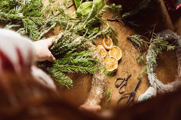 istock Florist hands making Christmas wreath on wooden tabletop with evergreen tree branches 1359508888