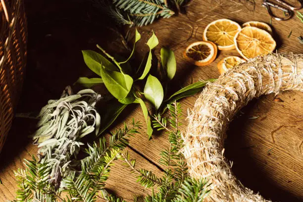 Female making a Christmas wreath in a DIY - Do It Yourself - work at home on a wooden table top with vintage scissors and tools.