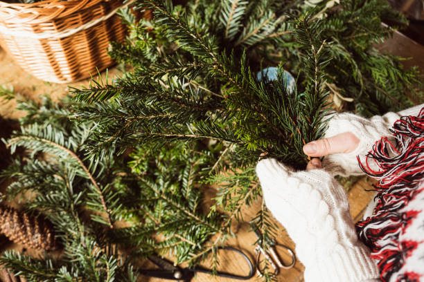 istock Florist hands making Christmas wreath on wooden tabletop with evergreen tree branches 1359509512
