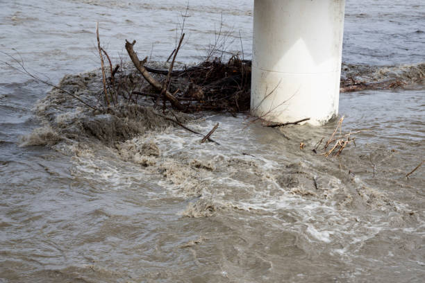 istock Branches of fallen trees got stuck at the bridge support after flooding in a muddy river. Flooding of mountain rivers after snowmelt, flooding 1359510157