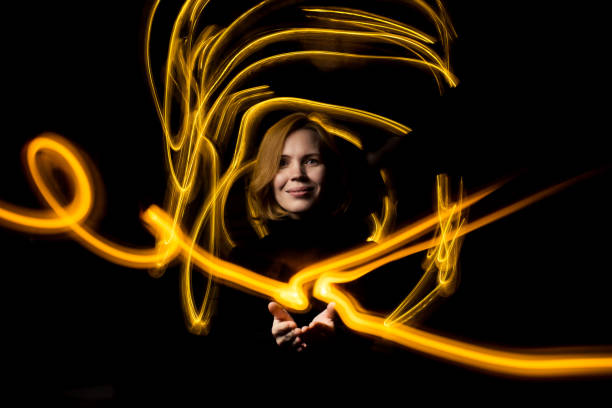 istock Woman surrounded by drawn light at long exposure. Energy flows concept. 1359515843