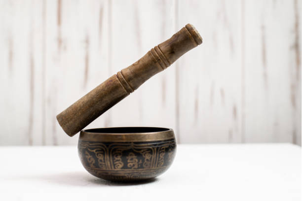 istock Singing bowl with a levitating stick on a light wooden background. 1359515895