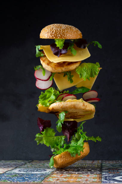istock Hamburger bun, double chicken cutlet with cheese, lettuce, arugula and radish. Meat, vegetables and bread. Ingredients. Homemade burger on a plate. Table made of colored tiles 1359519446
