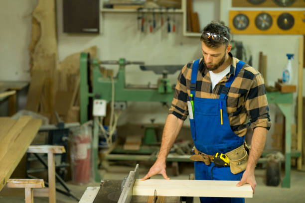 istock Handsome carpenter preparing, measures and cutting boards on cutting machine 1359519726