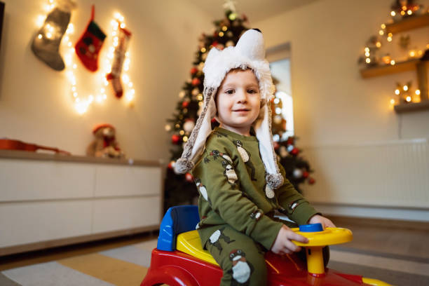 istock Playful toddler boy riding a plastic trunk toy, while wearing winter hat in wolf shape 1359520983