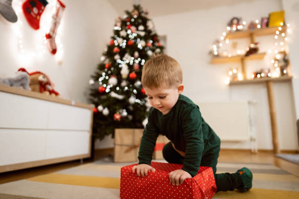 istock Toddler boy near Christmas tree playing with Christmas present 1359521510
