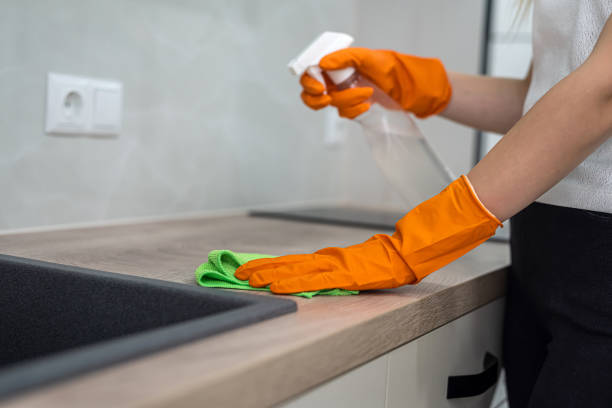 istock beautiful female hands in orange mittens wipe the kitchen surface from dust 1359521741