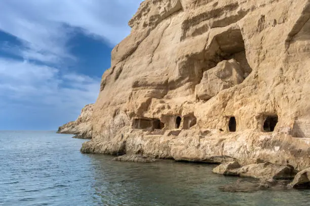 Photo of Stunning neolithic era caves on the cliff of Matala beach, Southern Crete, Greece. Used as historically used as living spaces and tombs
