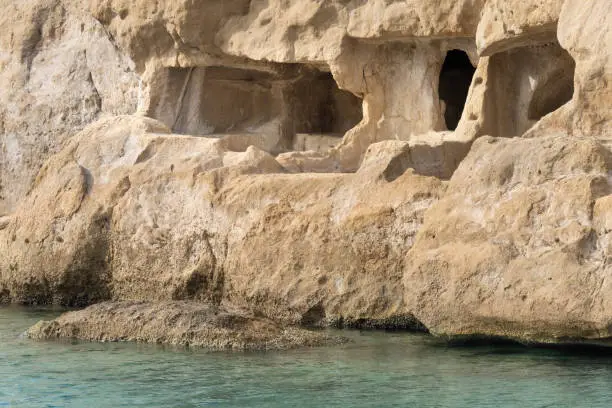 Photo of Stunning neolithic era caves on the cliff of Matala beach, Southern Crete, Greece. Used as historically used as living spaces and tombs