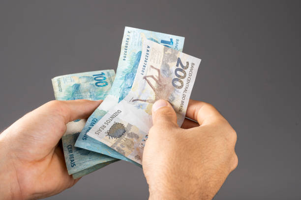 istock Hand of a man holding Brazilian notes Reais 1359522552