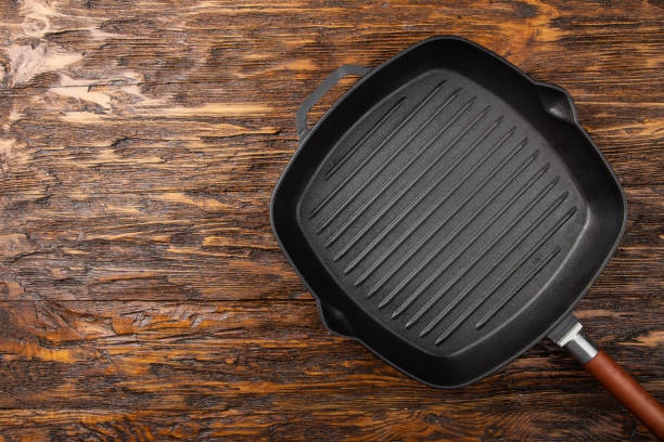 istock An empty black cast iron grill pan for cooking delicious meat. Wood background. Space for text. 1359524533