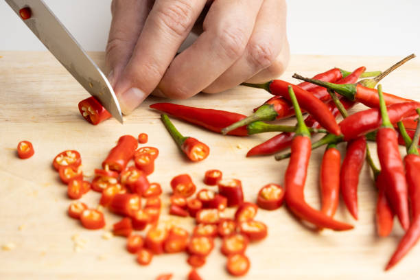 istock woman's hand is using a knife to cut red chili peppers for cooking. 1359527014