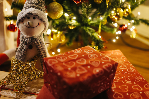 Close-up shot of smiling snowman toy and presents under Christmas tree