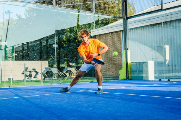 partita di padel in un campo da paddle in erba blu - bel ragazzo che gioca una partita - padel foto e immagini stock