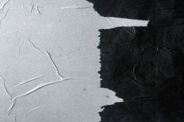 istock Black and white crumpled paper glued to the wall. 1359538475