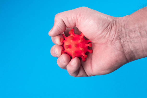 istock A man's hand squeezes the COVID-19 virus. 1359538640