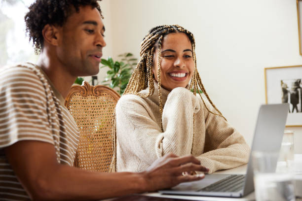 istock Smiling young woman using a laptop at home with her boyfriend 1359539708