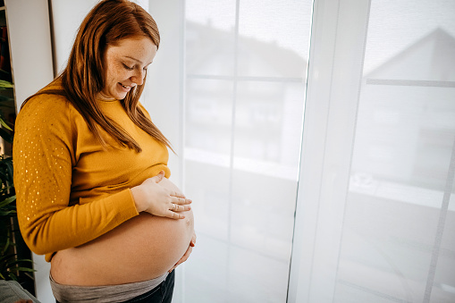 Pregnant woman standing near window