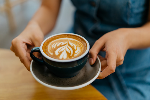 Woman holding a cup of cafe latte in cafe