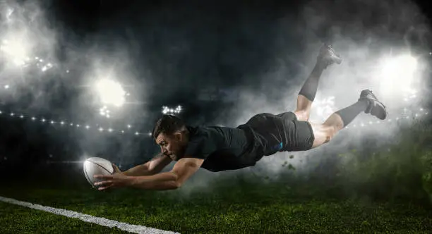 Try.  Rugby football player in action on dark arena background
